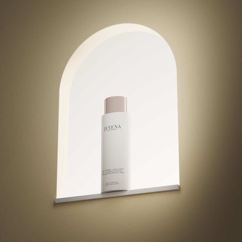 Weisse Flasche mit rosafarbenem Deckel in einer beleuchteten Nische. Juvena-Logo sichtbar.