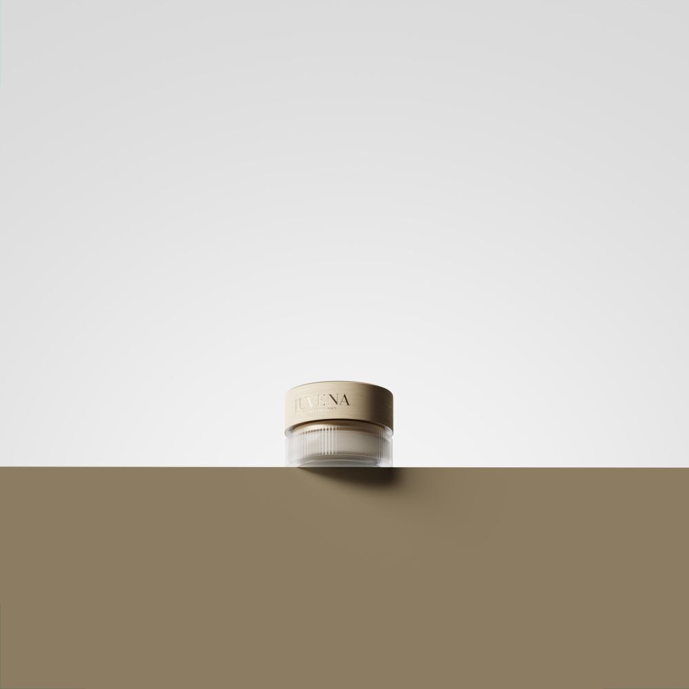 Creme-Glas mit goldfarbenem Deckel. Aufschrift: JUVENA. Auf braunem Untergrund. Weißer Hintergrund.