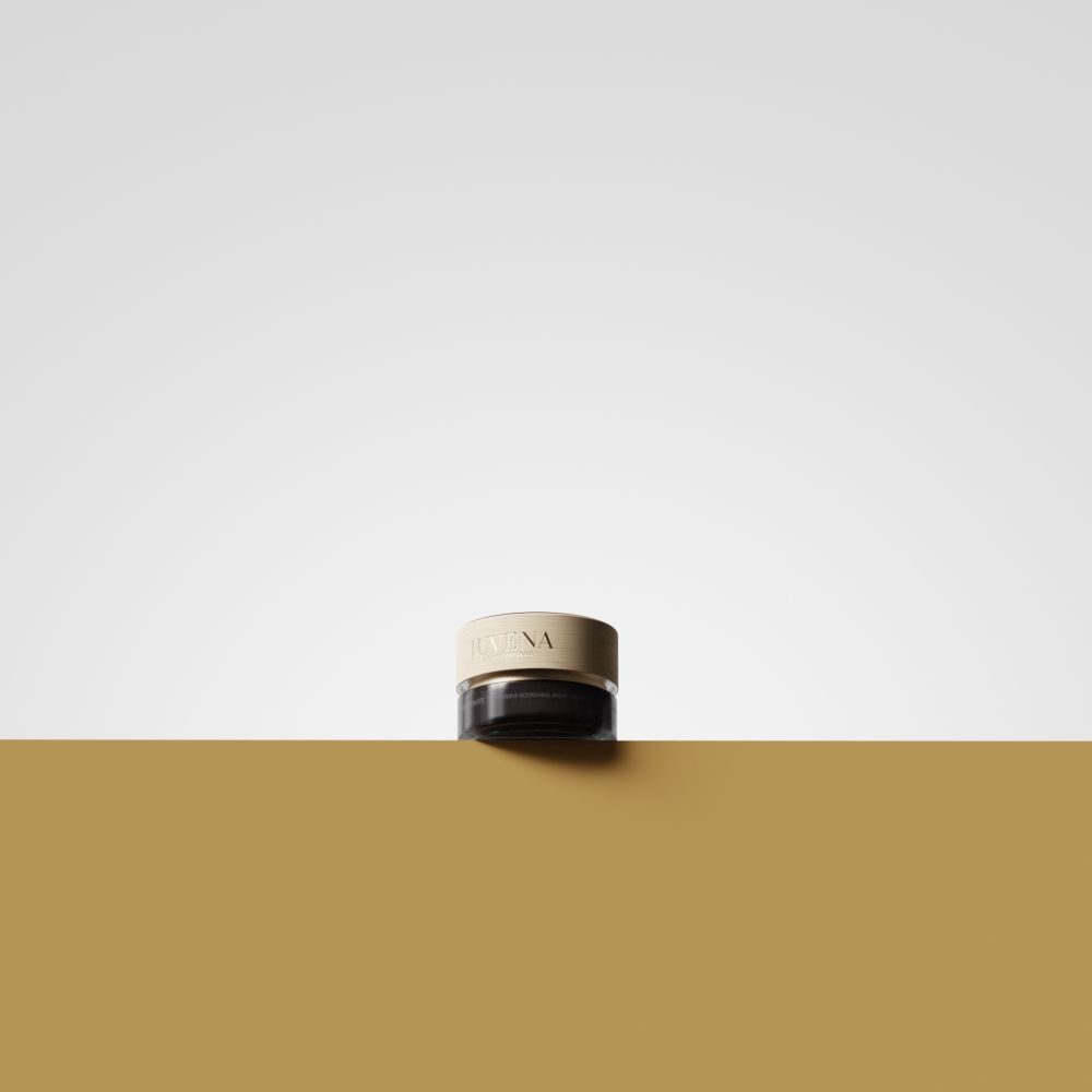 Creme-Dose mit goldenem Deckel. Aufschrift: JUVENA. Auf goldener Oberfläche platziert. Hintergrund: gelb und weiß.