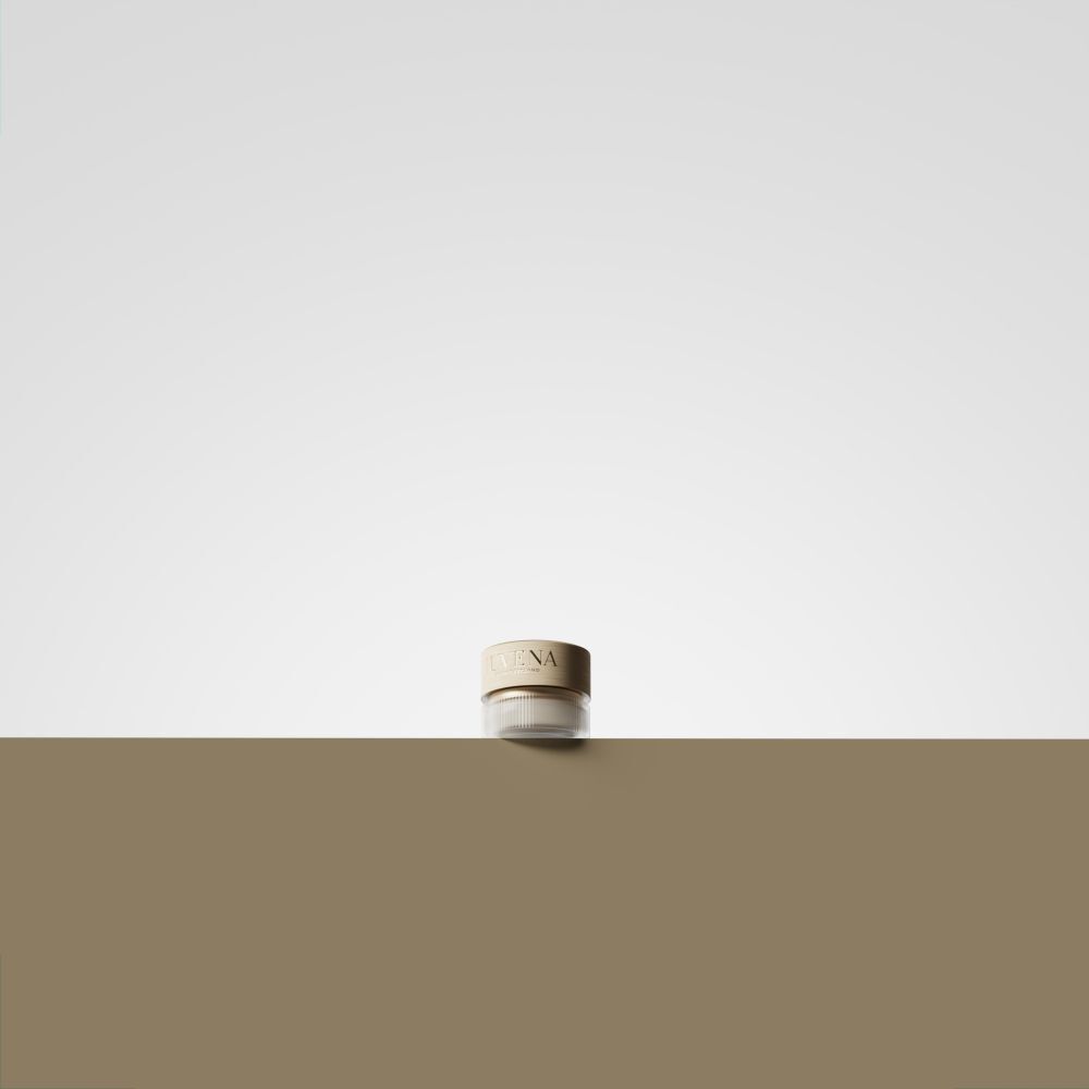 Creme-Glas mit goldfarbenem Deckel. Auf brauner Oberfläche.