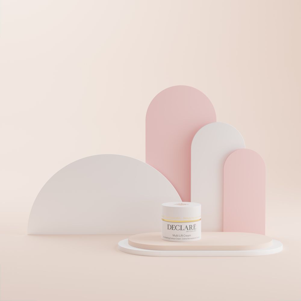 Creme-Tiegel auf Podest. DECLARÉ Multi Lift Cream. Hintergrund mit weißen und rosa Formen.