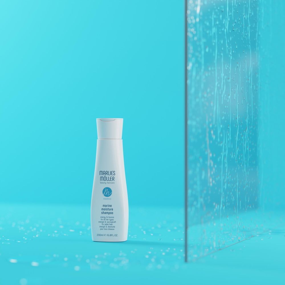 Shampoo-Flasche vor blauem Hintergrund und Glas. Aufschrift: Marlies Möller, Marine Moisture Shampoo.