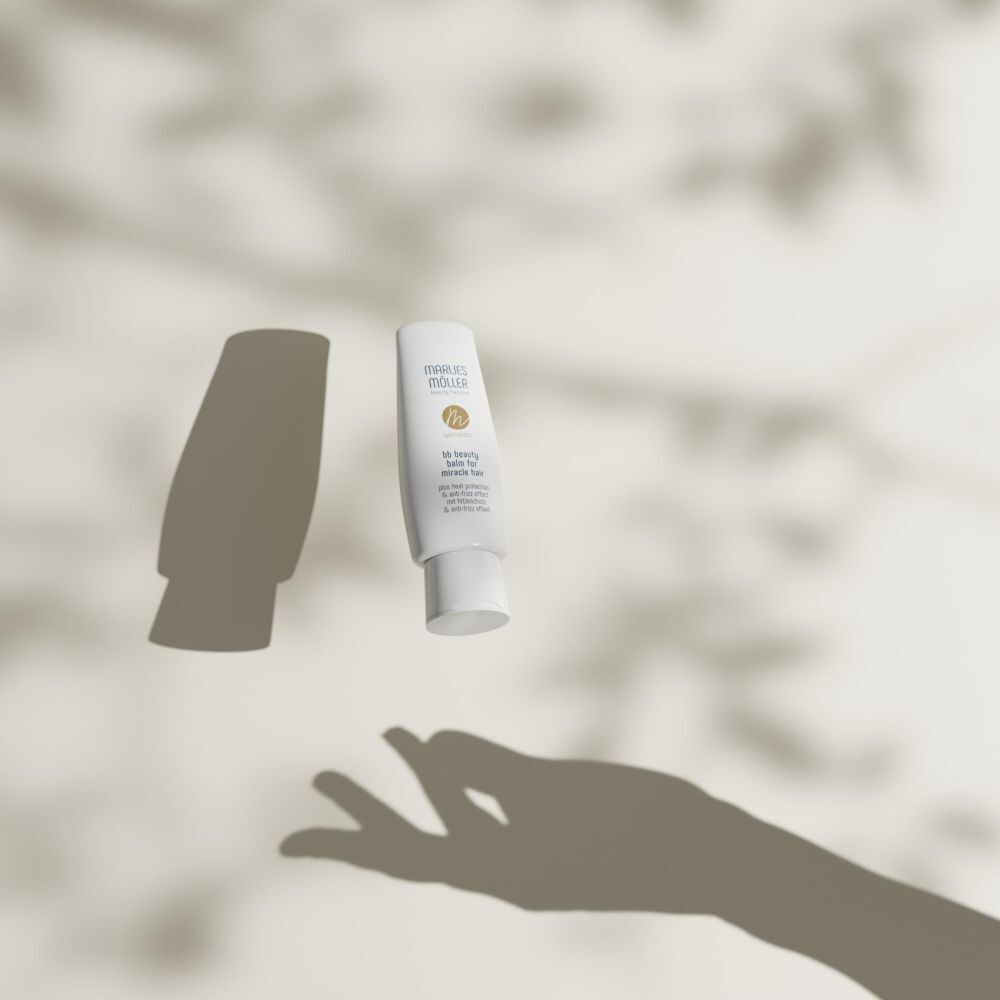 Weißer Flakon, Schatten einer Hand. Marke: Marlies Möller. Text: bb beauty balm for miracle hair. Mit Hitzeschutz & Anti-Frizz.