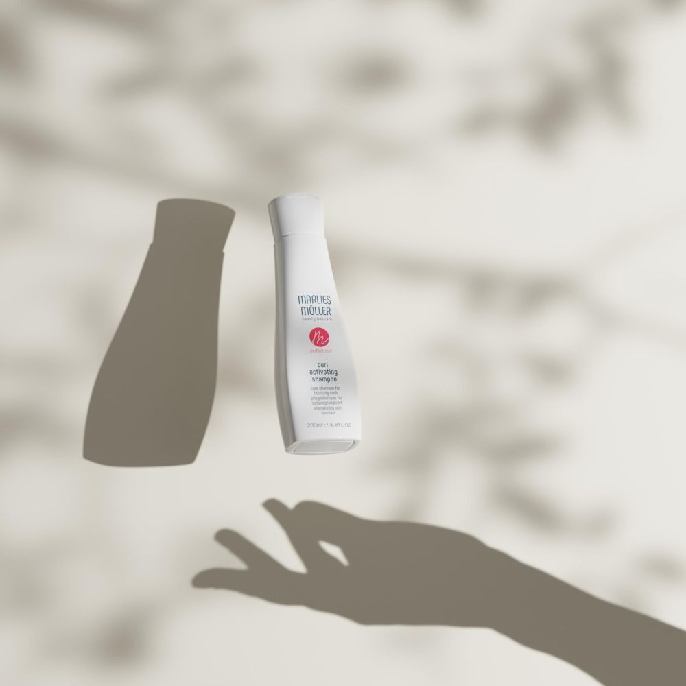 Schattenbild einer Hand und Shampoo-Flasche. Produktname und Logo sichtbar.