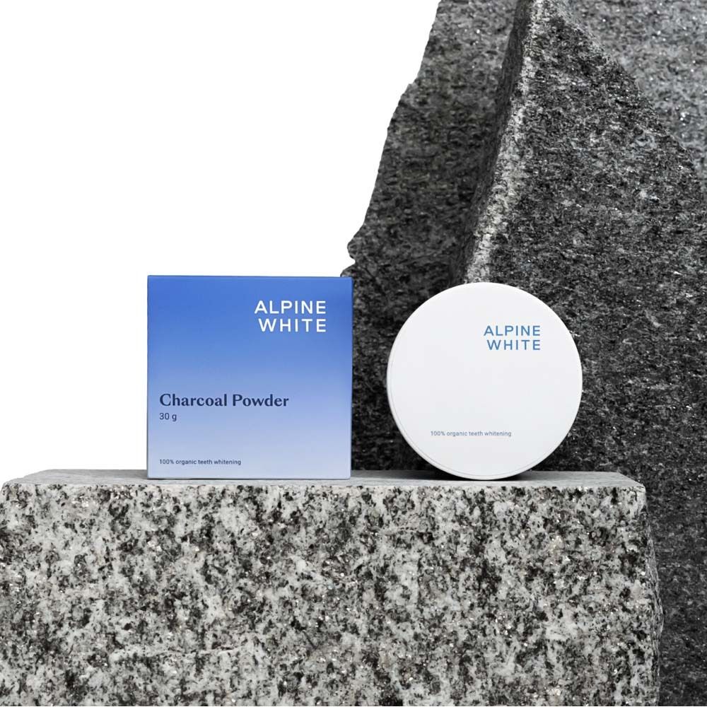 Blaue Schachtel und Dose auf Stein. Text: ALPINE WHITE, Charcoal Powder, 30 g.