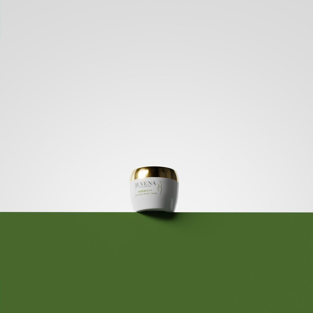 Weißes Cremetiegel mit goldenem Deckel auf grünem Hintergrund. Juvena, Fascionista.