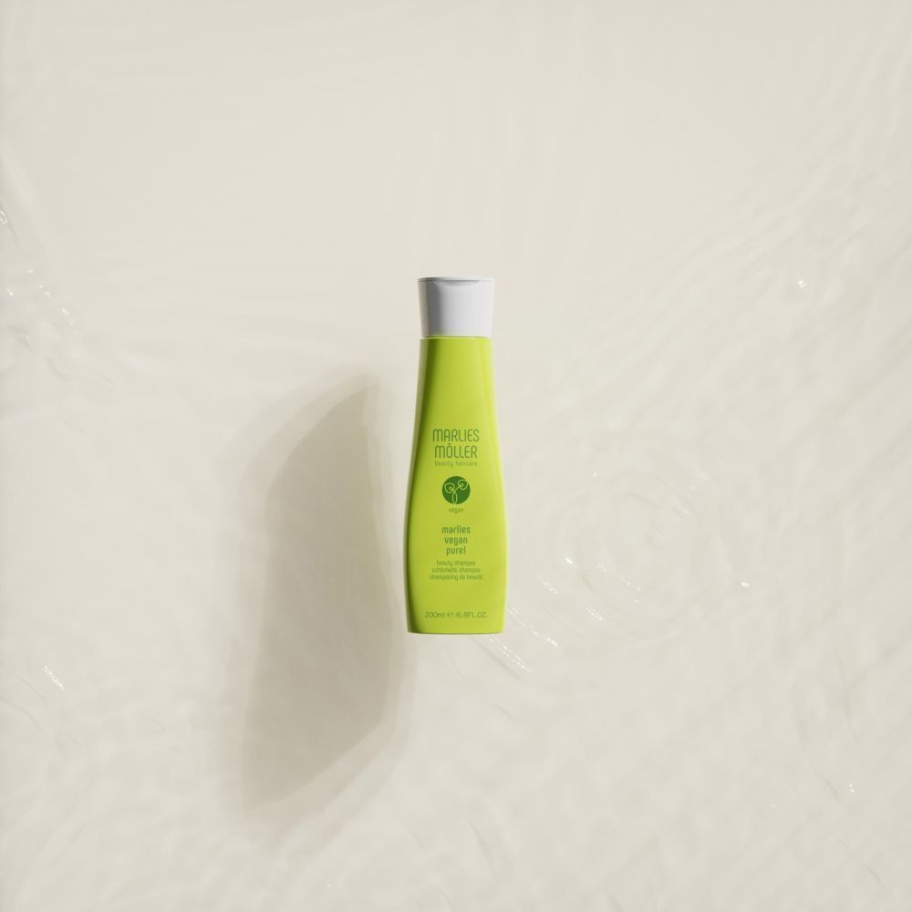 Grüne Shampoo-Flasche im Wasser. Aufschrift: Marlies Möller, Vegan Pure! Beauty Shampoo.