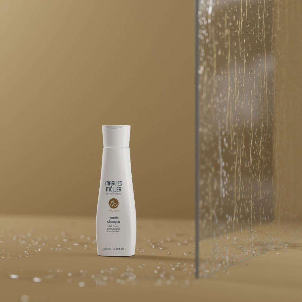 Marlies Möller Keratin Shampoo-Flasche vor Glaswand. Hintergrund beige, Wassertropfen.