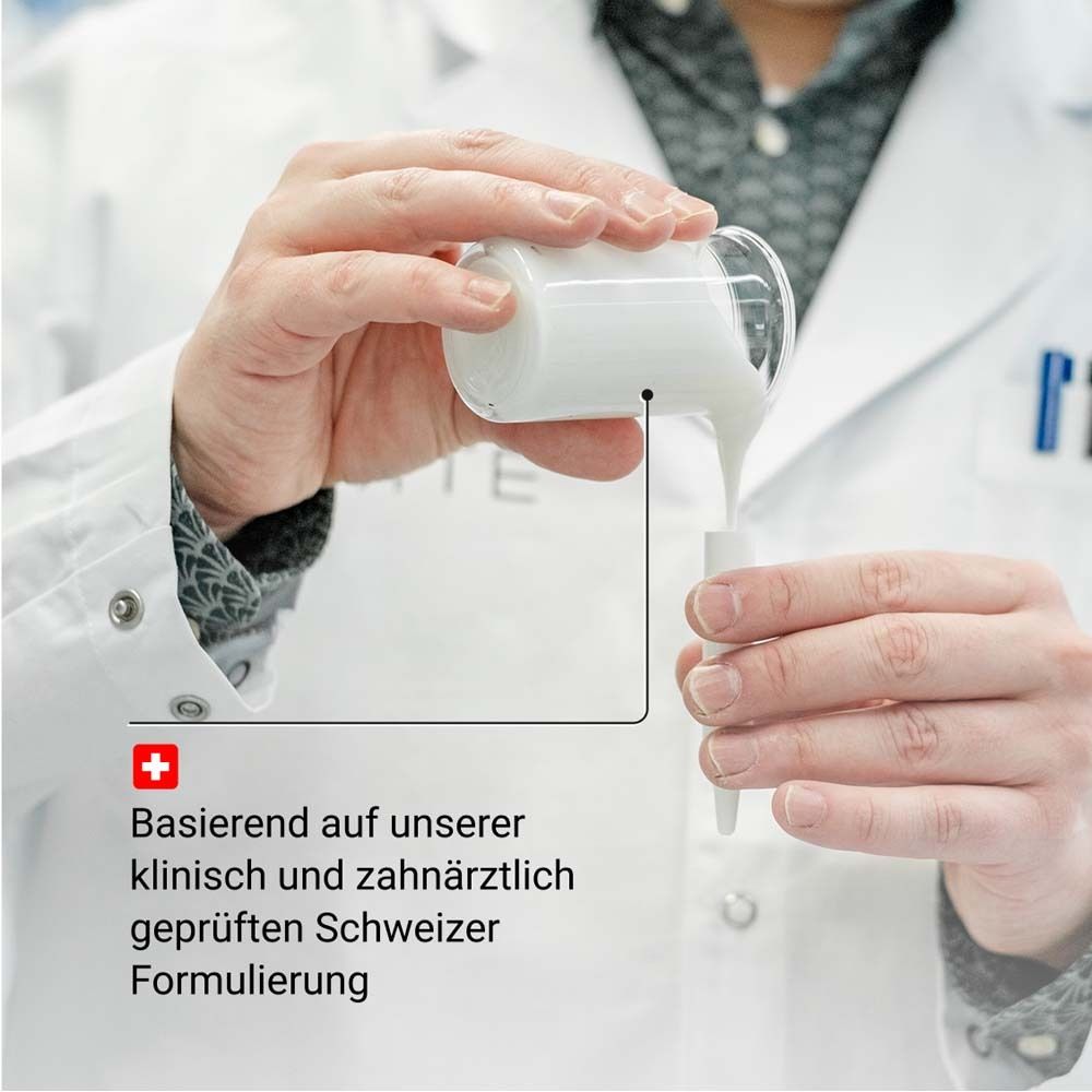 Hände gießen eine Flüssigkeit in ein kleines Gefäß. Text: klinisch und zahnärztlich geprüfte Schweizer Formulierung.