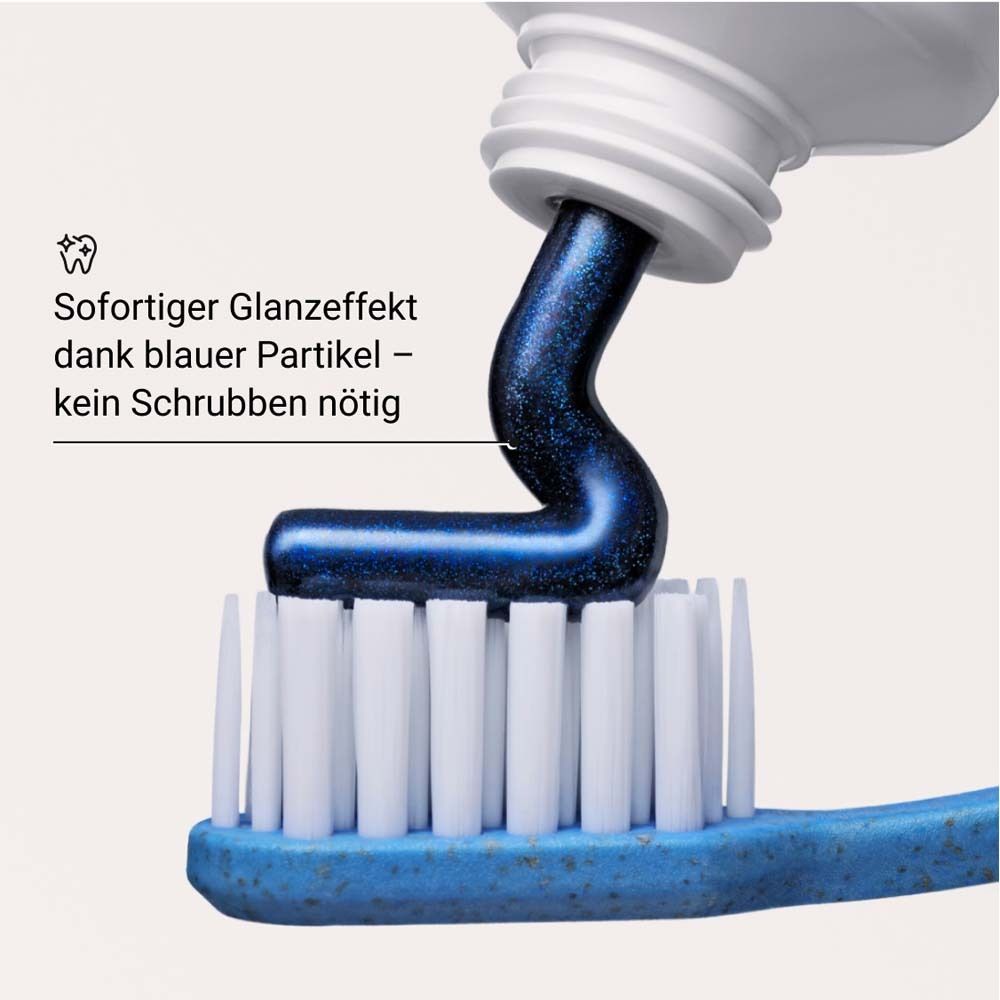 Blaue Zahnpasta auf einer Zahnbürste. Text: Sofortiger Glanzeffekt dank blauer Partikel – kein Schrubben nötig.