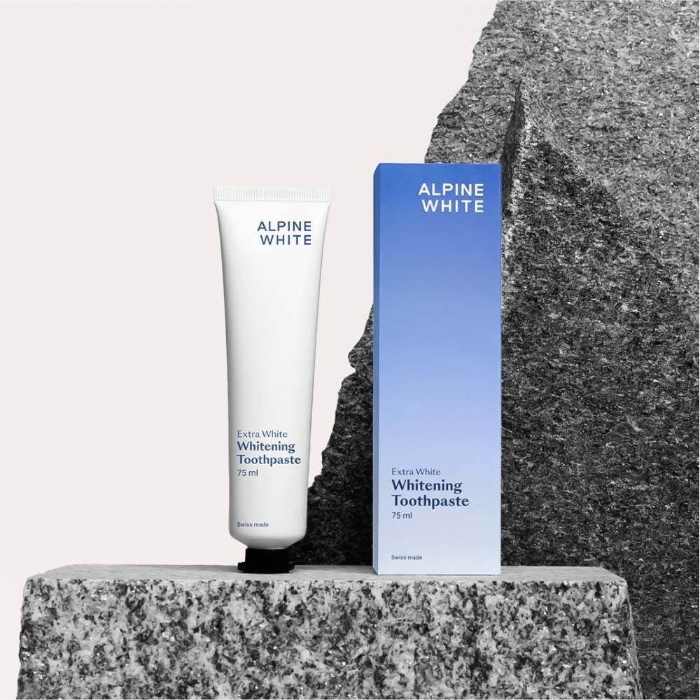 Zahnpasta-Tube und Schachtel auf einem Stein. Aufschrift: ALPINE WHITE, Extra White Whitening Toothpaste, 75 ml.