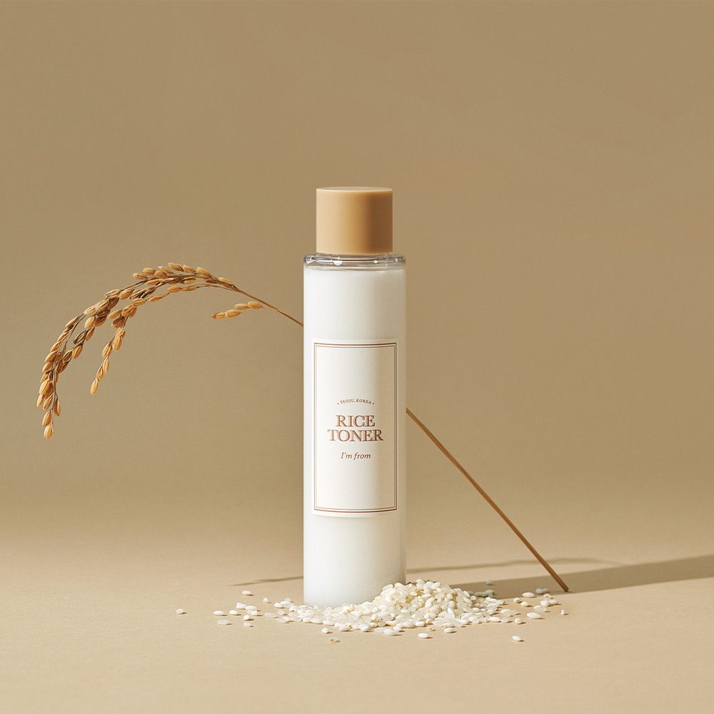 Weiße Flasche mit beige-goldenem Verschluss, Etikett 'RICE TONER'.