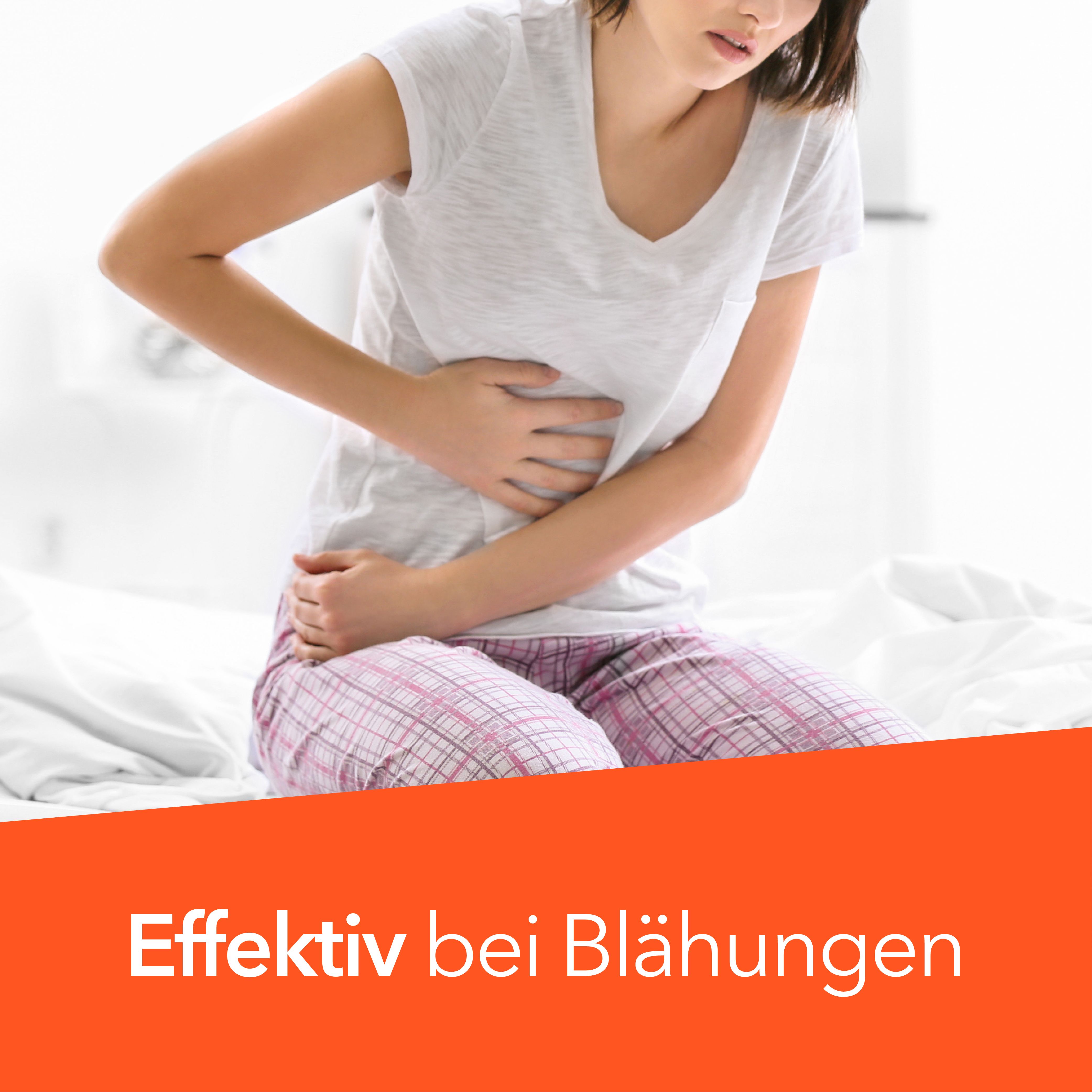 Frau sitzt auf Bett, hält Bauch. Orange Balken mit Text: Effektiv bei Blähungen.