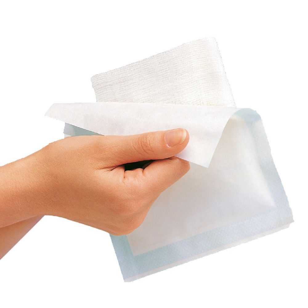 Hand hält Mullkompressen. Weiße Kompressen mit blauem Rand. Einzelne Kompresse wird geöffnet.