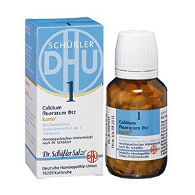 Braune Tabletten in einer Braunglasflasche mit weißem Deckel. Aufschrift: Calcium fluoratum D12 karto. Mit Umverpackung.