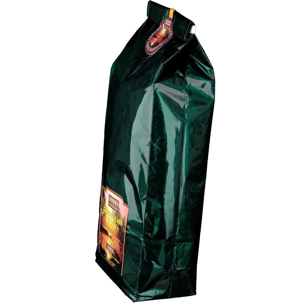 Grüne, glänzende Verpackung im Profil. Siegel mit Logo oben. Aufdruck mit Landschaftsmotiv und Schriftzug.