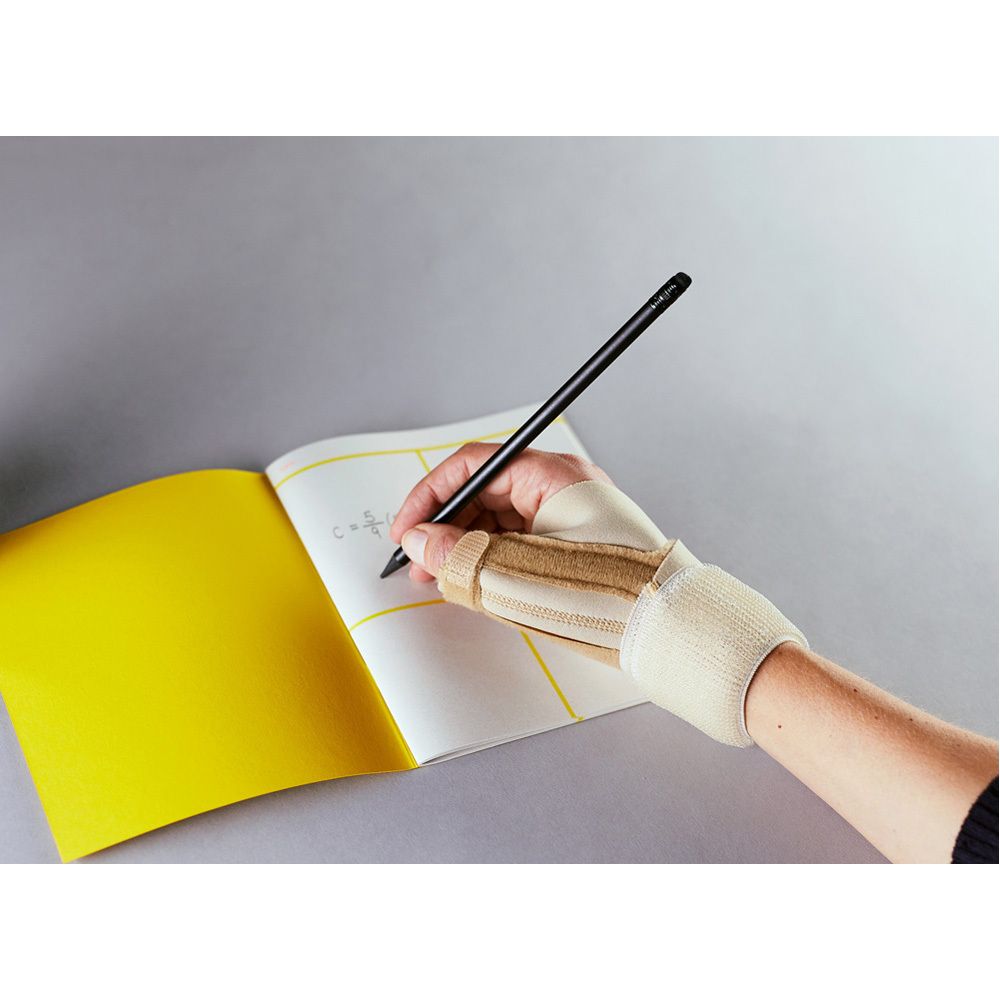 Person schreibt mit einem Stift auf ein gelbes Notizbuch. Die Person trägt eine FUTURO Daumen-Schiene.