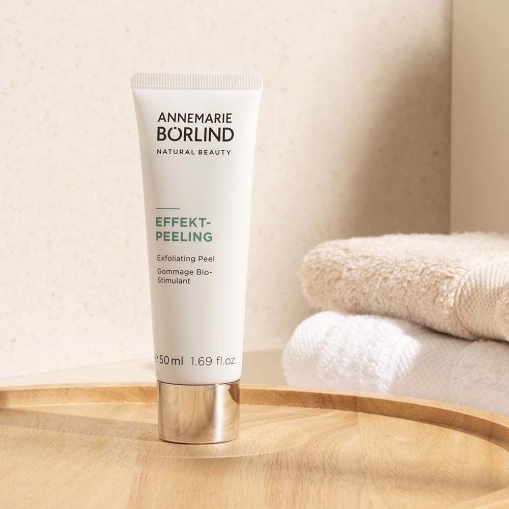 Weiße Tube EFFEKT-PEELING von ANNEMARIE BÖRLIND auf Holztablett neben Handtüchern.