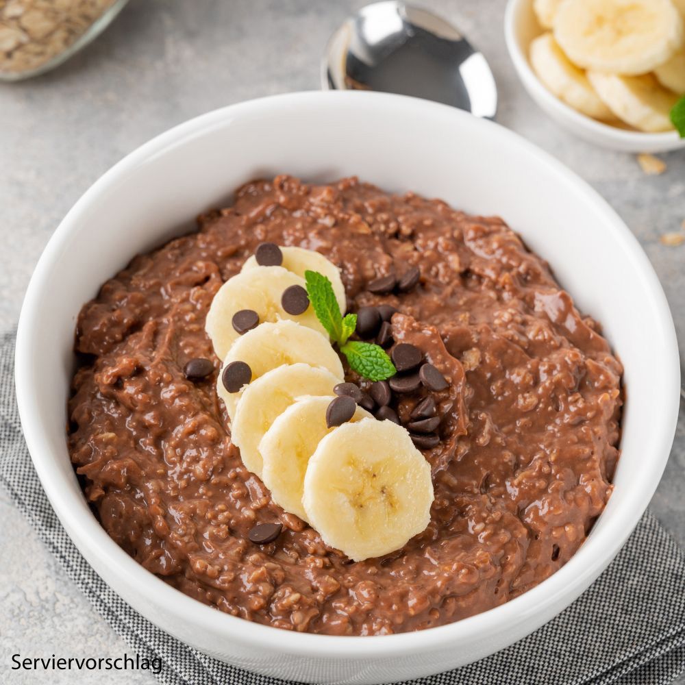 Schokoladen-Haferbrei mit Bananenscheiben und Schokostückchen. Servierbeispiel.