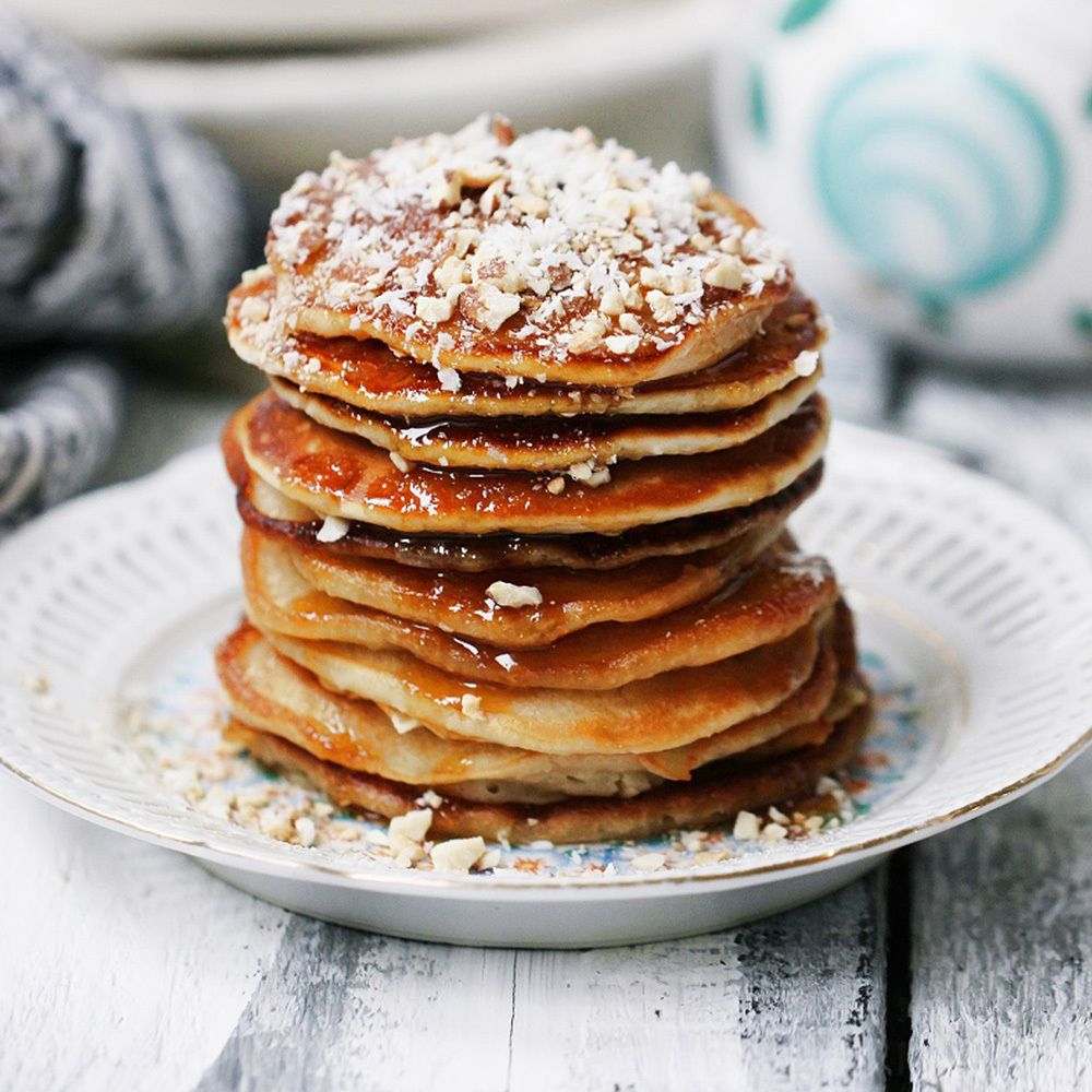 Stapel Pfannkuchen mit brauner Flüssigkeit und Nüssen. Auf einem Teller.