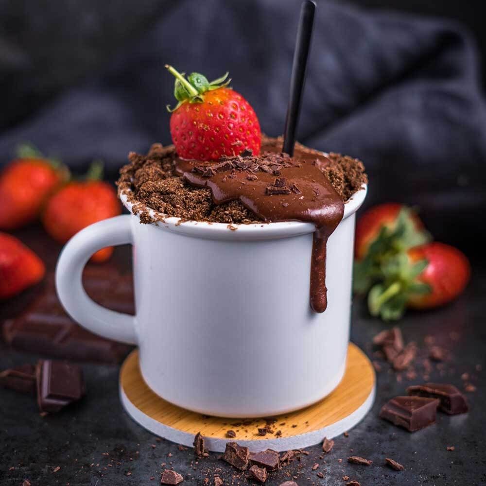 Becher mit Schokoladenkuchen, Erdbeere, Schokoladenstückchen. Auf Holzuntersetzer.