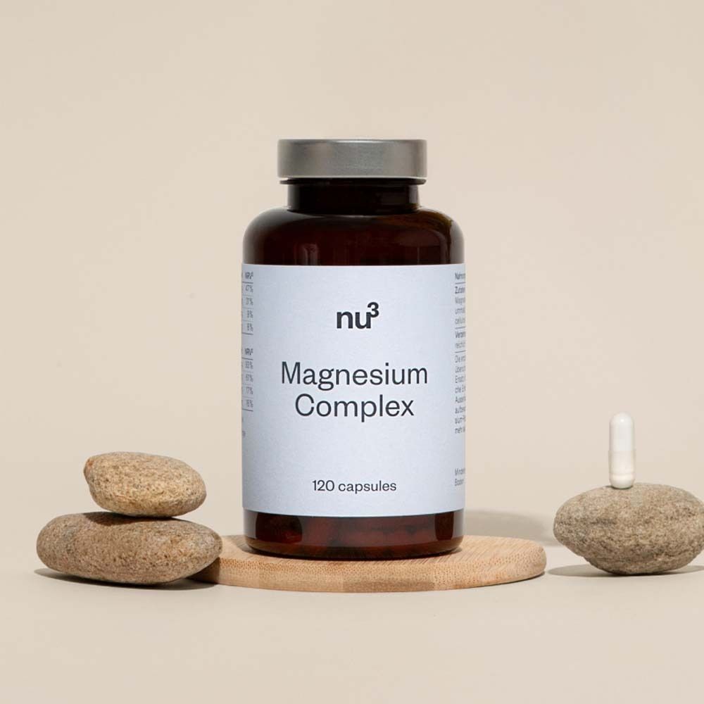 Braune Flasche mit weißem Etikett, Aufschrift „Magnesium Complex“ und „120 capsules“. Auf Holzplatte mit Steinen.