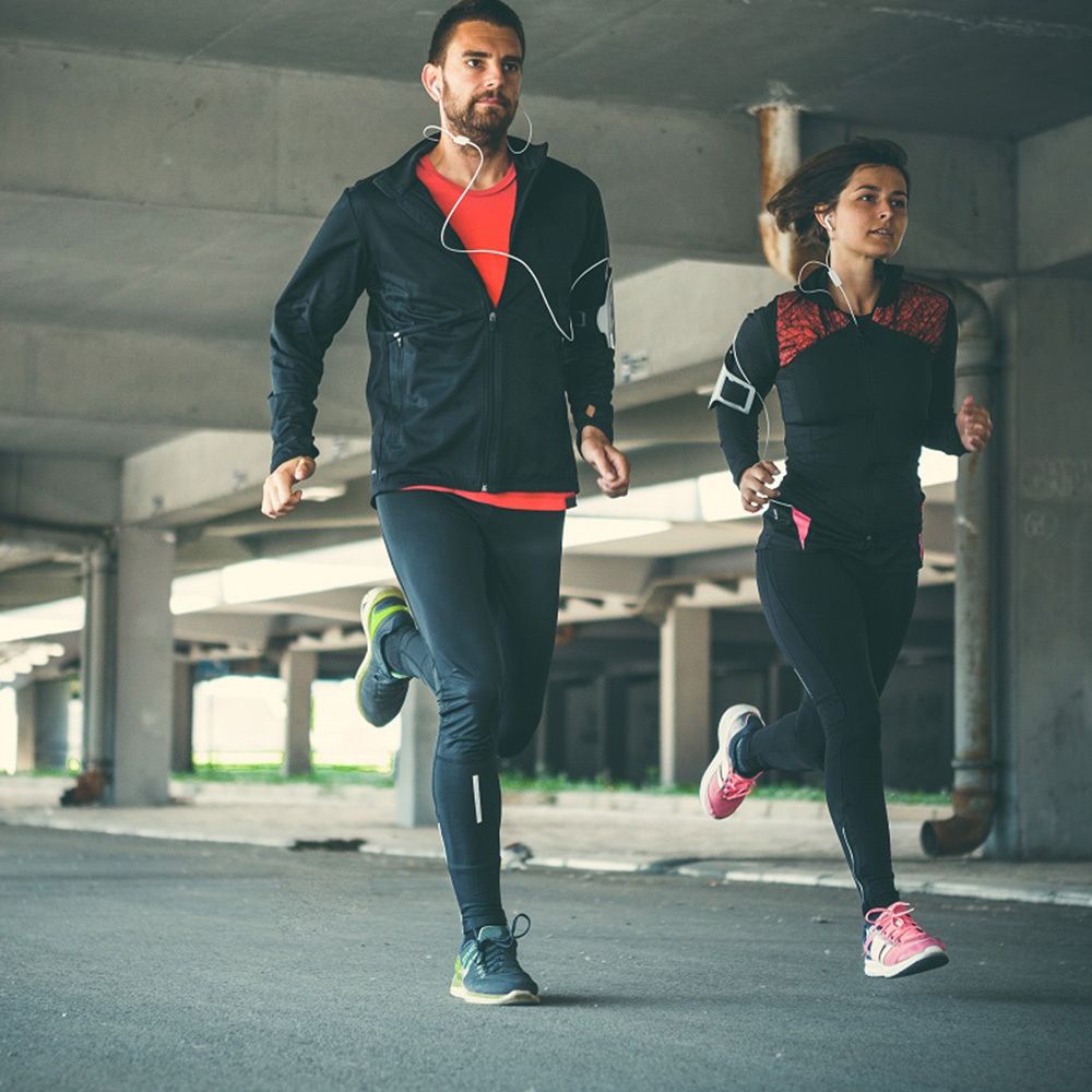 Zwei Läufer, Mann und Frau, in Sportkleidung. Laufen auf einer Straße unter einer Brücke. Sportliche Aktivität.