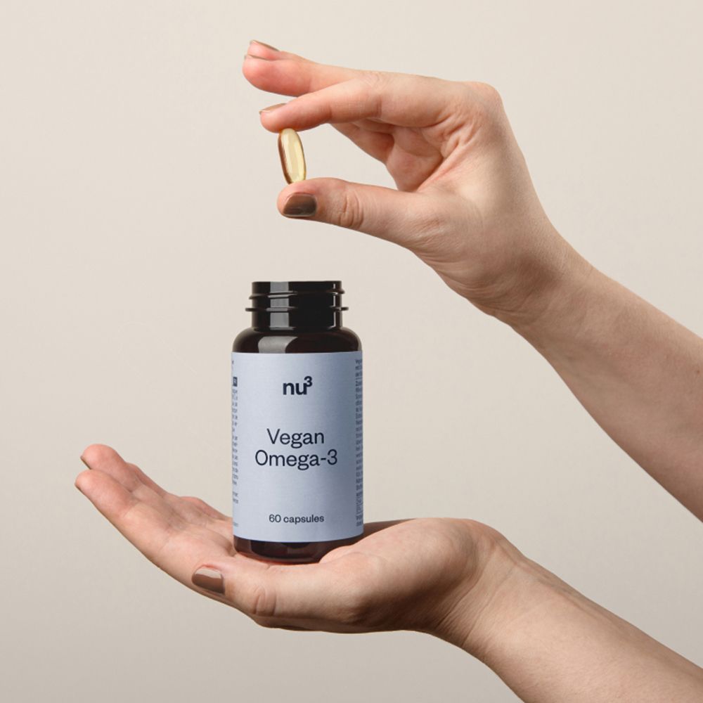 Hände halten eine Kapsel über einer Flasche. Aufschrift: nu3 Vegan Omega-3, 60 Kapseln.