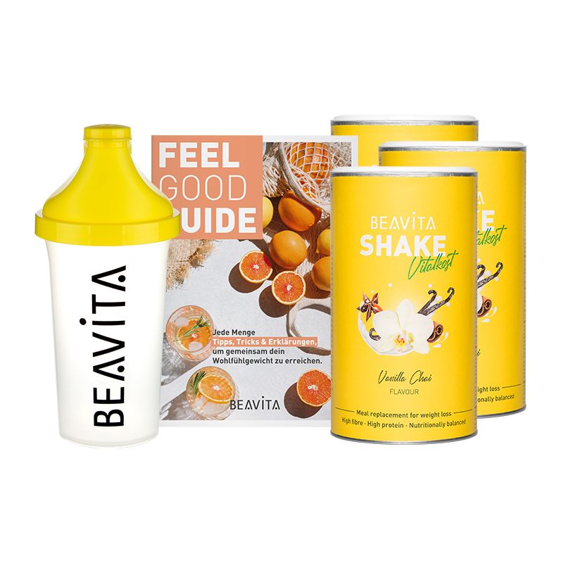 Diät-Paket mit Shaker, Broschüre und Dosen. Dosen mit "BEAVITA Shake Vital+kost Vanilla Chai". Shaker gelb-weiß. Broschüre mit Obst.