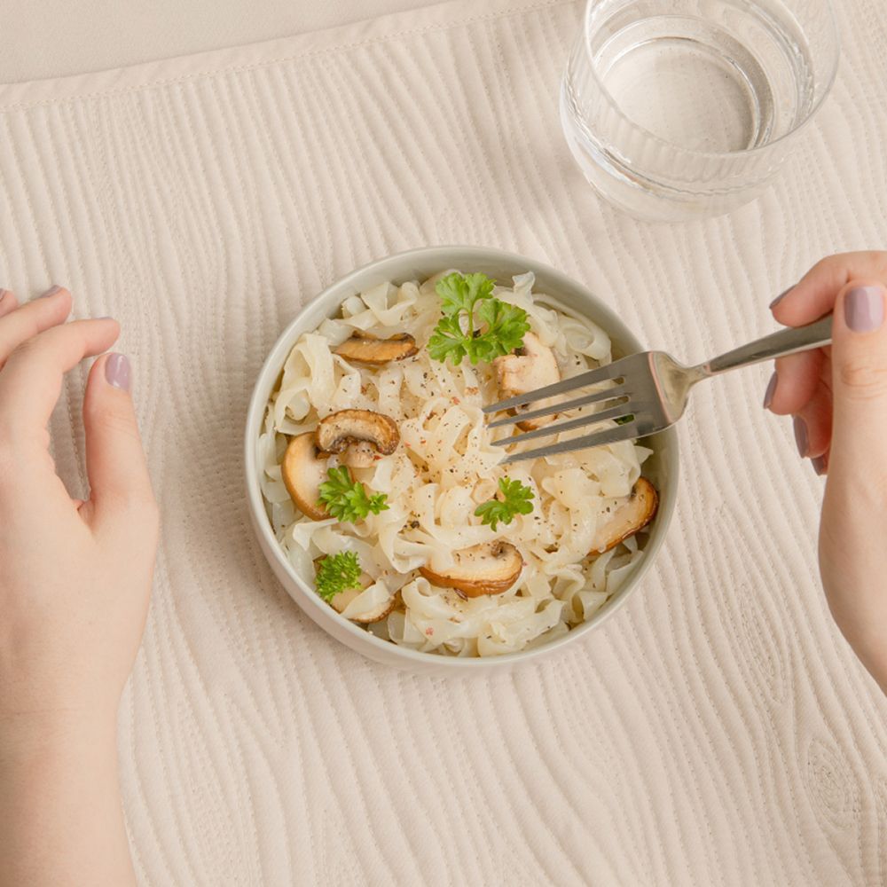 Eine Schüssel nu3 Fit Konjak-Tagliatelle mit Pilzen und Petersilie, von oben gesehen.