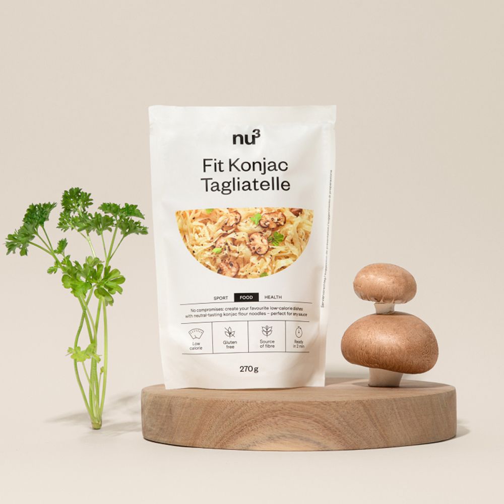 Eine Packung nu3 Fit Konjak-Tagliatelle auf einem Holzpodest mit Pilzen und Petersilie.