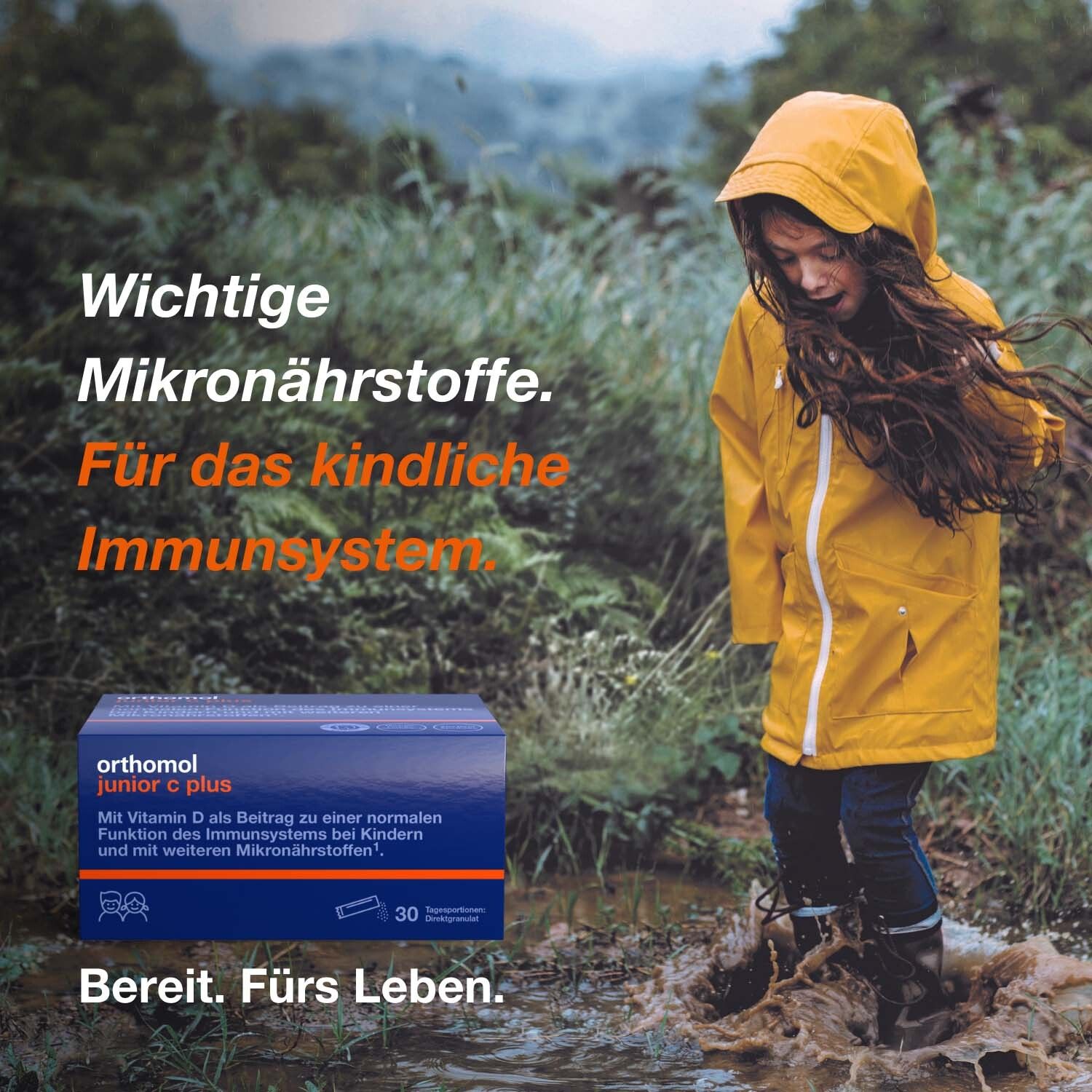 Kind in gelber Jacke steht im Wasser. Orthomol junior C plus-Packung. Text: Für das kindliche Immunsystem.