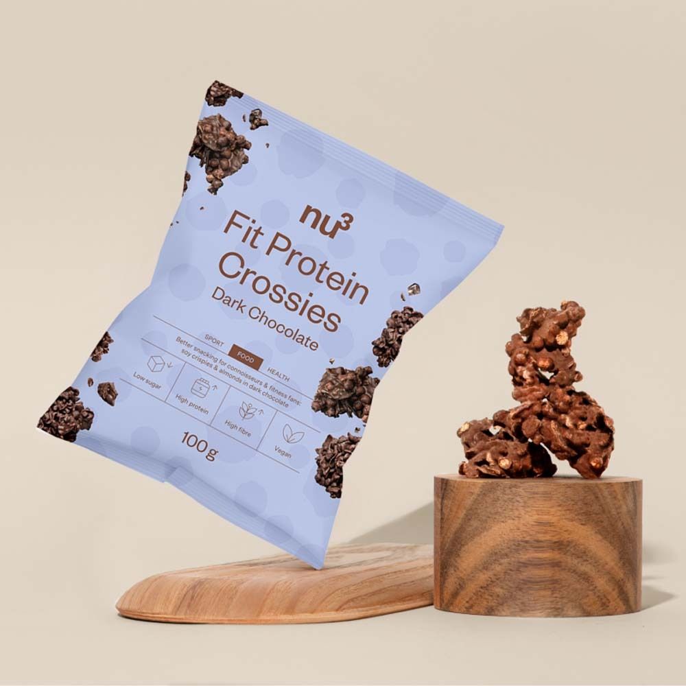 Verpackung von nu3 Fit Protein Crossies Dark Chocolate. Auf einem Holzsockel und -brett platziert. Produktpräsentation.