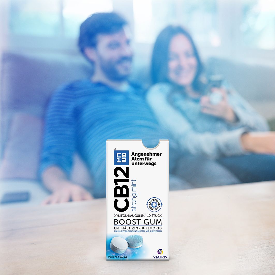 Personen auf einer Couch. In der Hand eine Packung CB12 Boost Strong Mint Kaugummi. Text: Angenehmer Atem für unterwegs.