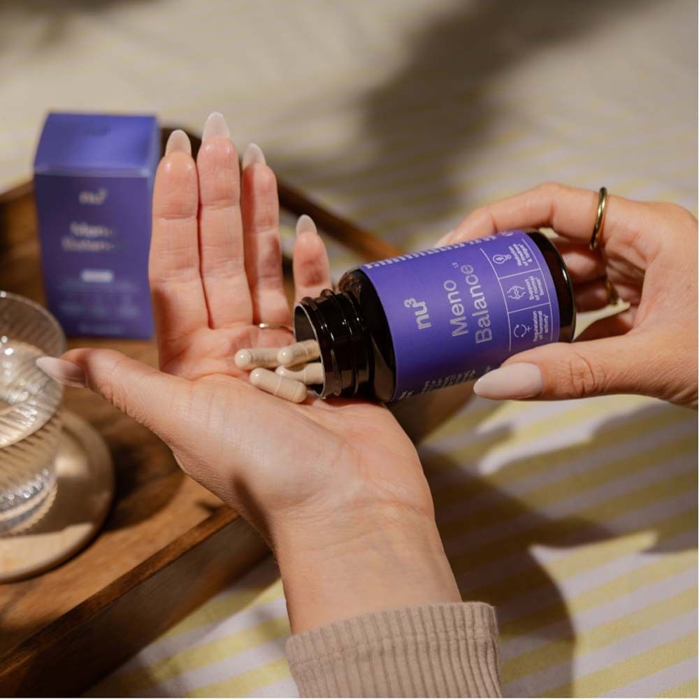 Hände halten Kapseln aus einer Flasche. Aufschrift: Meno Balance. Marke: nu3. Lila Etikett.