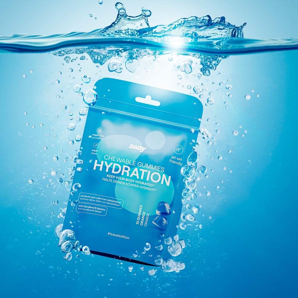 Blaue Verpackung von "sway CHEWABLE GUMMIES HYDRATION" im Wasser. Wasser spritzt. "Jet set friendly". Enthält 10 Orangen-Gummis.