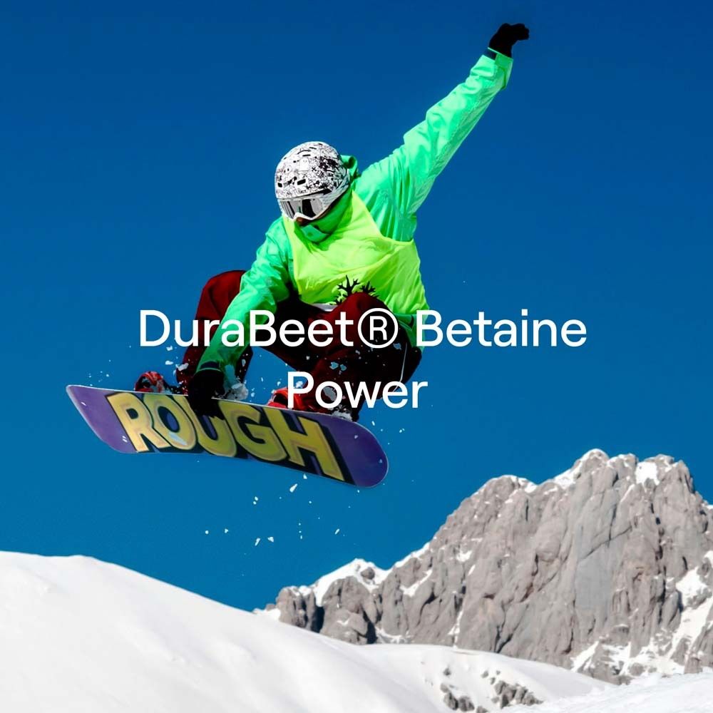 Snowboarder in der Luft. Text: "DuraBeet® Betaine Power". Berg im Hintergrund. Blauer Himmel.