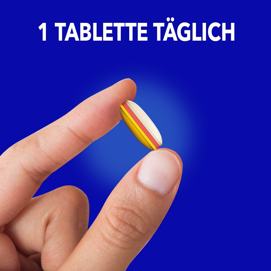 Hand hält eine gelb-rot-farbene Tablette. Aufschrift: 1 Tablette täglich.