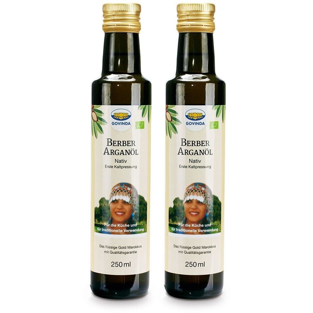 Zwei Flaschen Berber Arganöl. Dunkle Glasflaschen mit goldenen Verschlüssen. Etikett mit Produktname, Frauengesicht und Bio-Siegel.