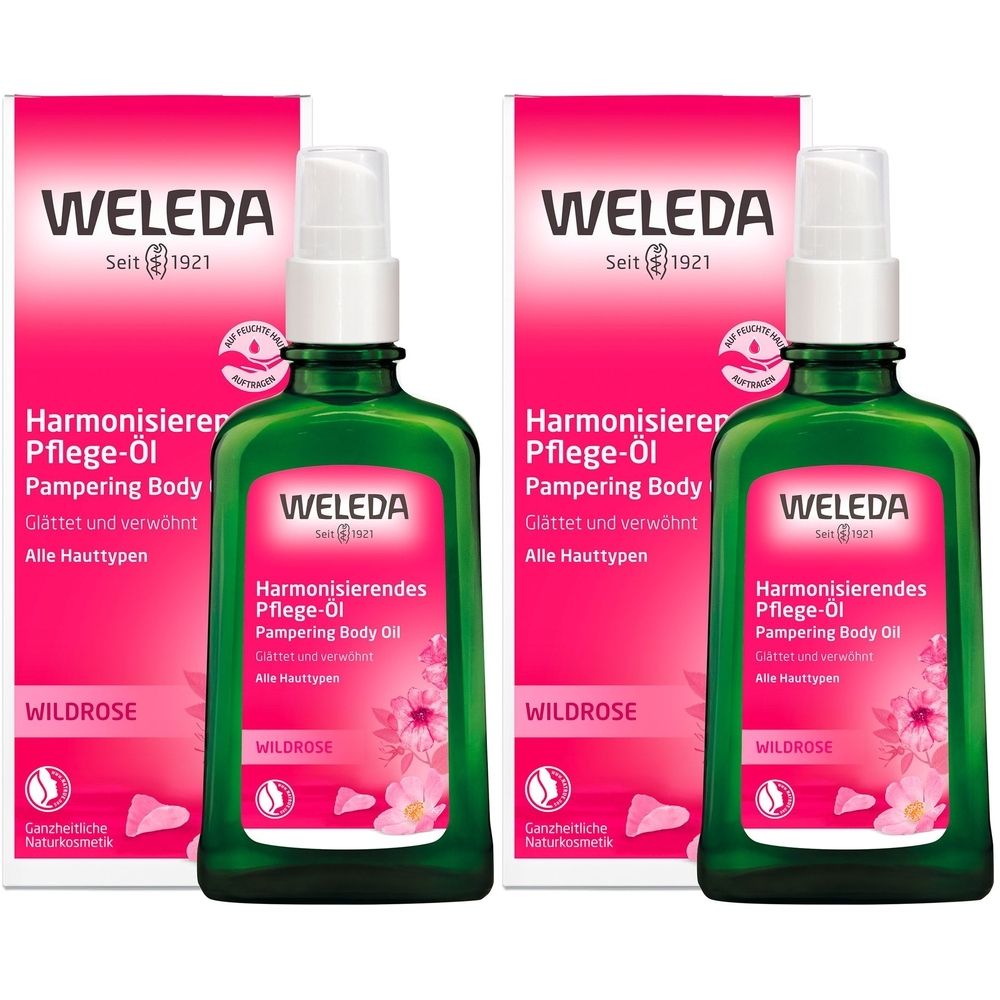 Zwei grüne Flaschen mit Sprühkopf und rosa Verpackung. Aufschrift: Weleda, Harmonisierendes Pflege-Öl, Wildrose. Für alle Hauttypen.