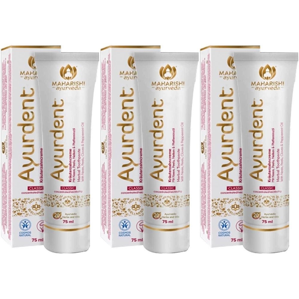 Mehrere Tuben und Schachteln Ayurdent Zahncreme Classic. Die Tuben sind weiß mit goldfarbenen und roten Akzenten. Aufdrucke: Marke, Produktname, Inhaltsstoffe.