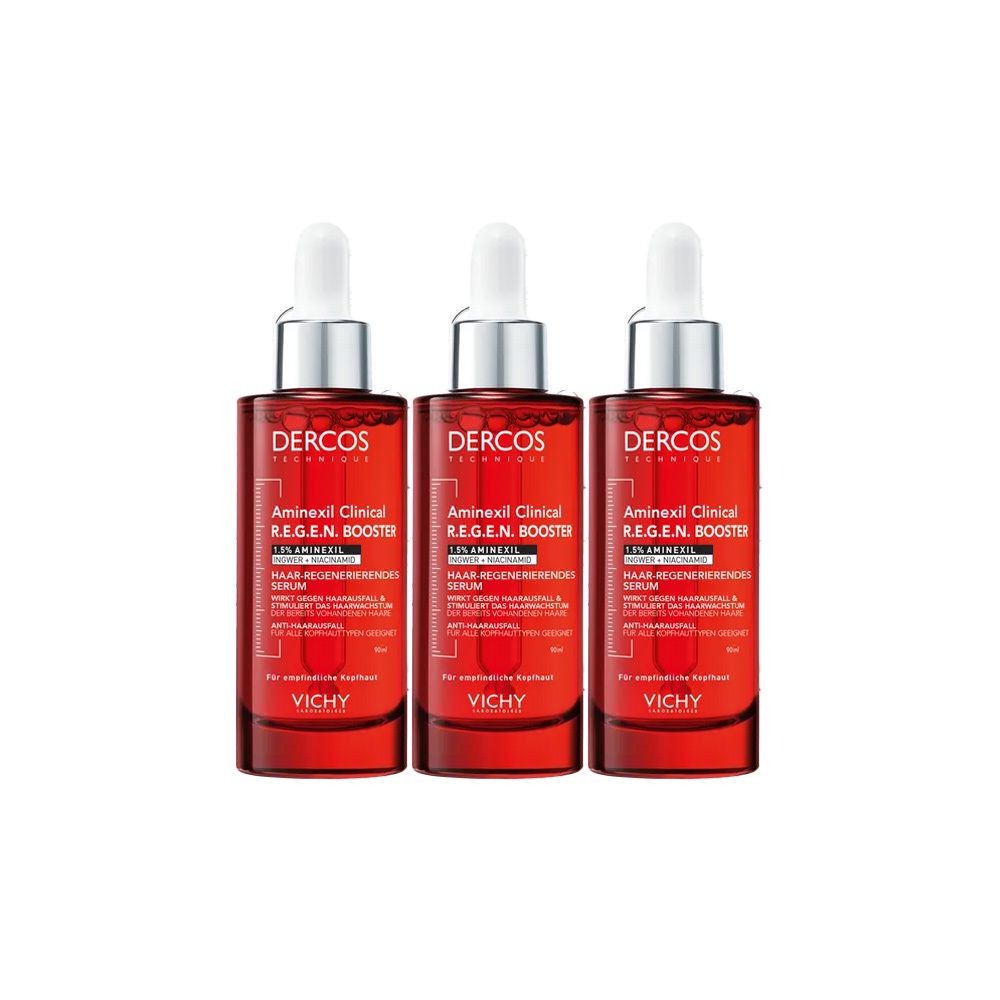 Drei Flaschen mit roter Flüssigkeit, silbernen Deckeln und weißen Pipetten. Auf jeder Flasche steht "DERCOS" und "Aminexil Clinical R.E.G.E.N. Booster".