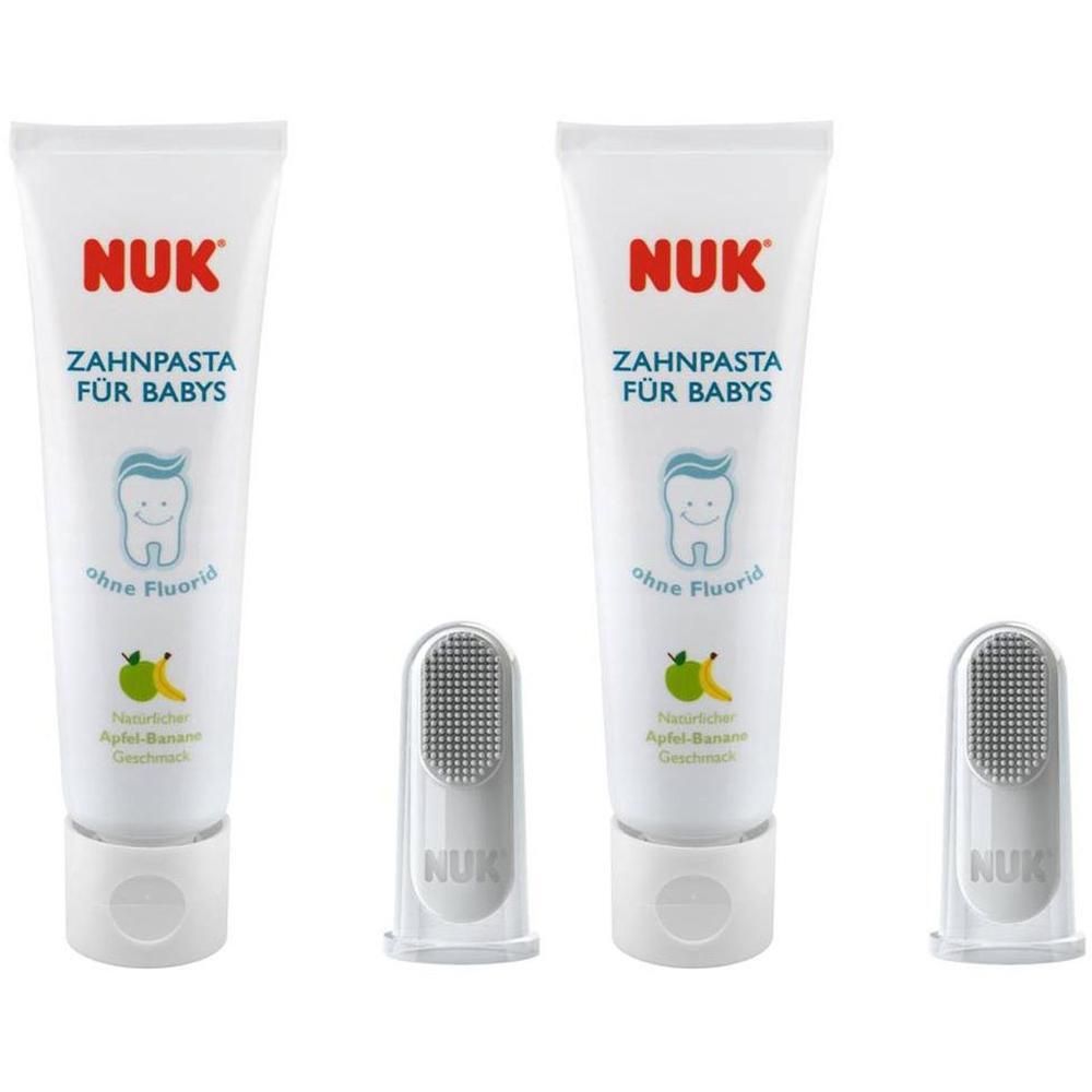 Zwei Tuben Zahnpasta und zwei Fingerzahnbürsten. Auf den Tuben steht "NUK ZAHNPASSTA FÜR BABYS". Ohne Fluorid. Natürlicher Apfel-Banane Geschmack.
