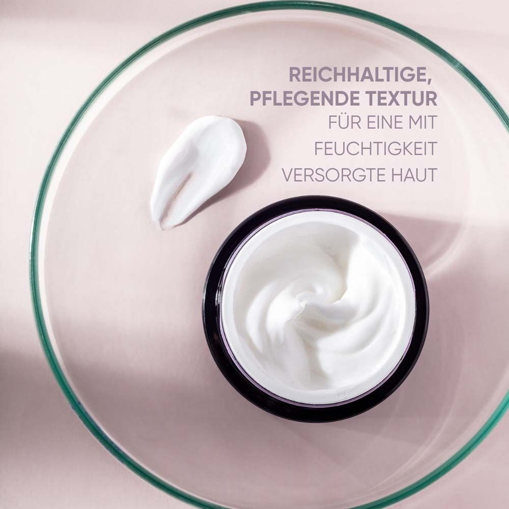 Creme in einem Tiegel auf einer Glasplatte. Daneben ein Klecks Creme. Rosa Hintergrund.