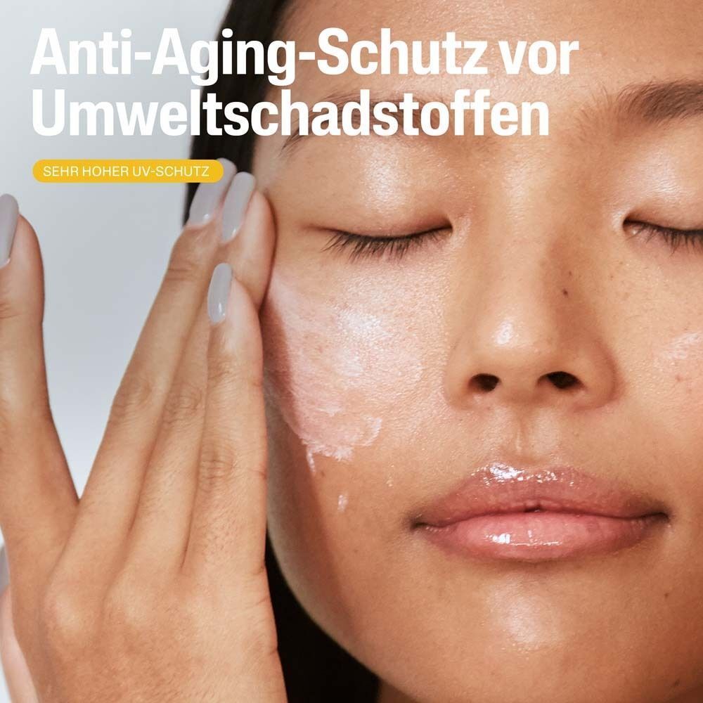Nahaufnahme einer Person, die Creme auf ihr Gesicht aufträgt. Text: Anti-Aging-Schutz vor Umweltschadstoffen. Sehr hoher UV-Schutz.