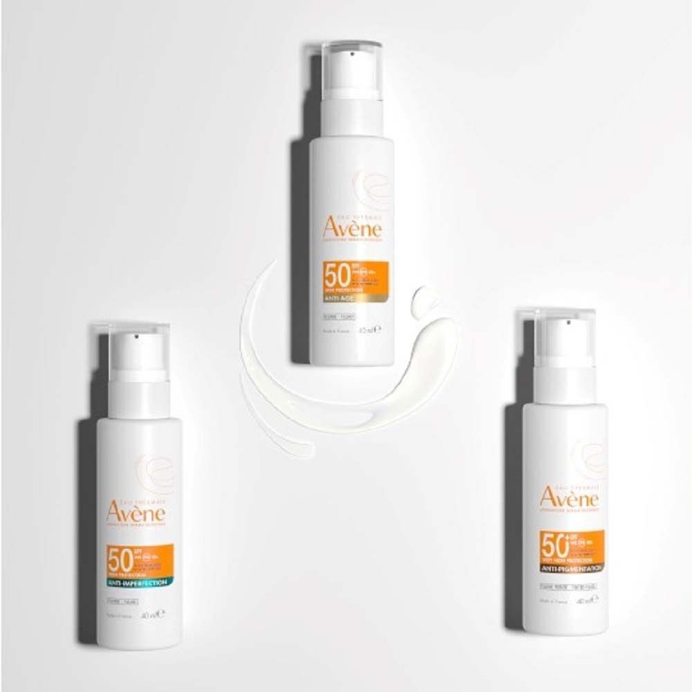 Drei weiße Flaschen AVENE Anti-Imperfection Fluid SPF 50 mit Pumpverschluss, umgeben von einem weißen Klecks Creme.
