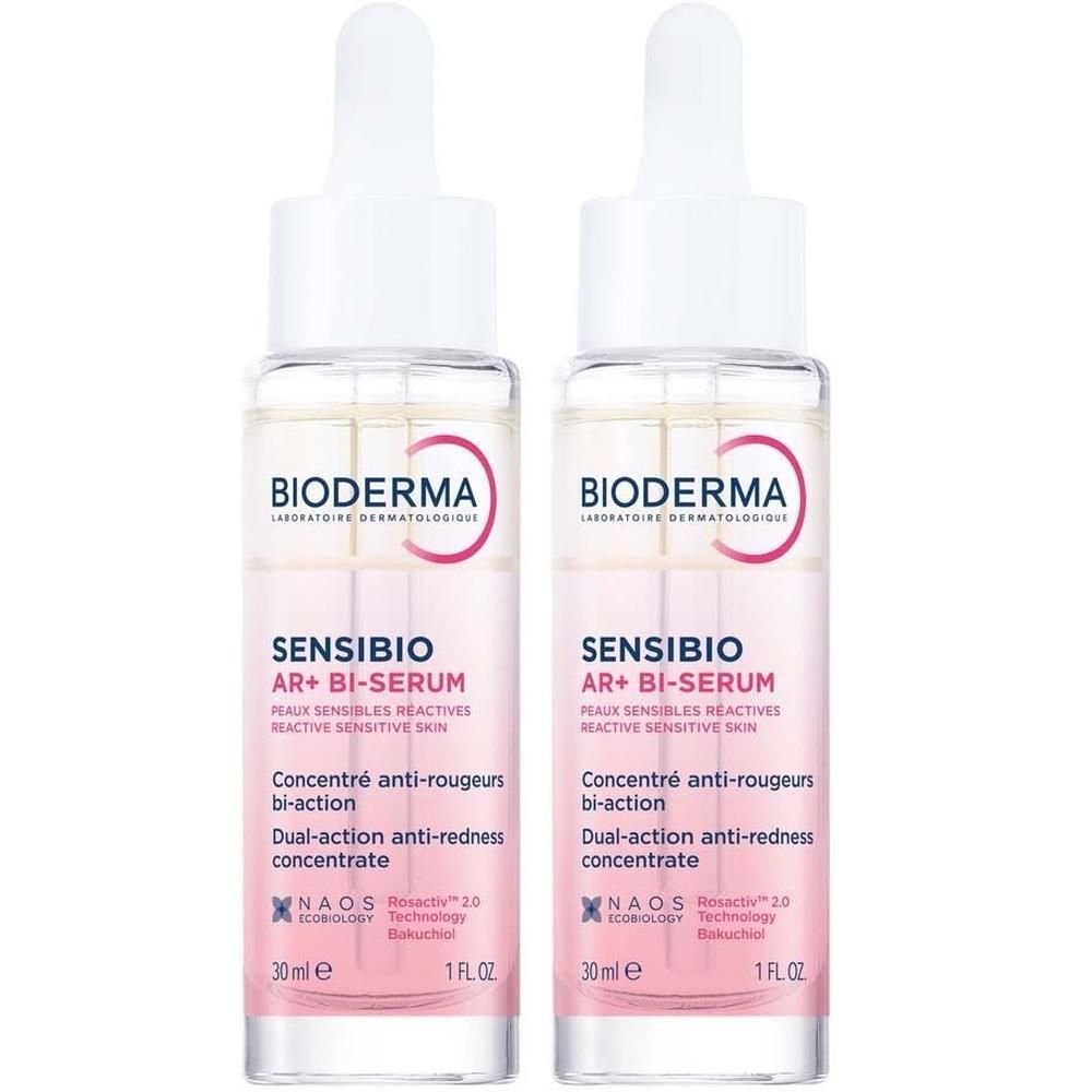 Zwei Flaschen Sensibio AR+ Bi-Serum. Klare Glasflaschen mit weißem Deckel und Pipette. Rosa Etikett mit Produktinformationen.