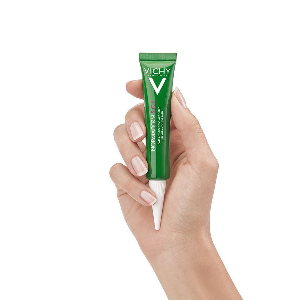 Hand hält eine grüne Tube mit weißer Spitze. Marke VICHY.