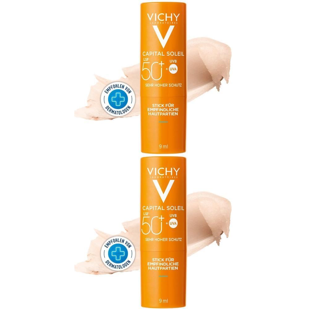 Zwei orangefarbene Stifte mit weißem Aufdruck. Aufschrift: VICHY, CAPITAL SOLEIL LSF 50+. Empfohlen von Dermatologen. Mit cremefarbenem Produktstrich.