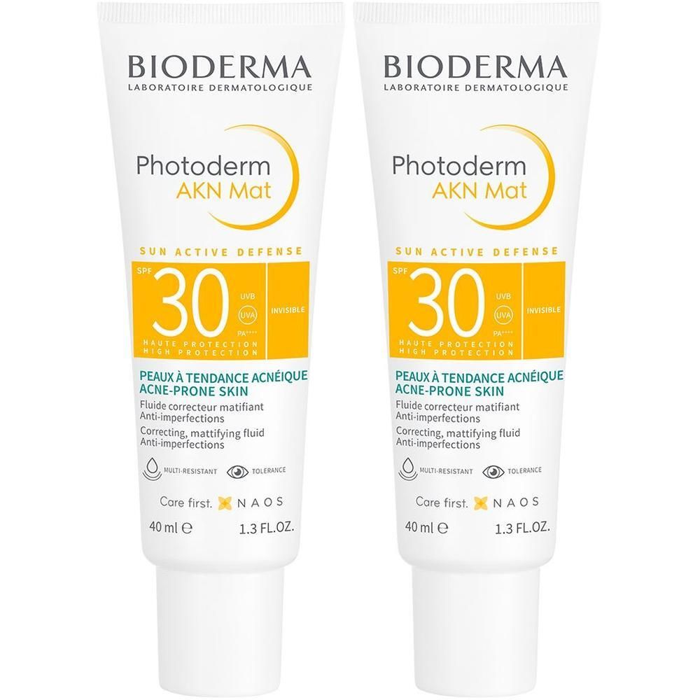 Zwei Tuben BIODERMA Photoderm AKN Creme SPF 30. Weiße Tuben mit gelben Akzenten. Text: Photoderm AKN, SPF 30, für zu Akne neigende Haut.